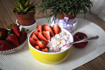 Fresh organic strawberries with muesli porridge in a yellow clay bowl