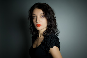 Fototapeta premium Studio portrait of sexy brunette woman with red sensual lips looking at the camera posing on black background