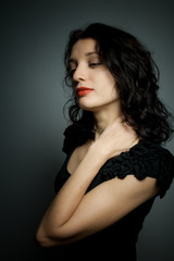 Naklejka premium Sexy brunette woman with red sensual lips posing on black background with closed eyes for pleasure