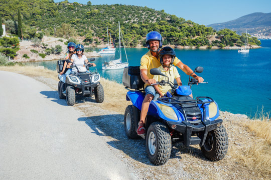 Family riding quad bike. Cute boy and his father on quadricycle. Motor cross sports on Greece island. Family summer vacation activity.