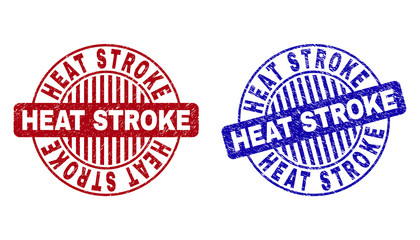 Grunge HEAT STROKE round stamp seals isolated on a white background. Round seals with grunge texture in red and blue colors. Vector rubber imprint of HEAT STROKE title inside circle form with stripes.