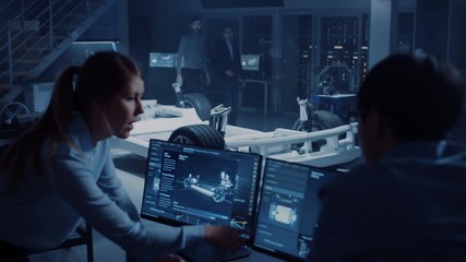 Female and Male Engineers are Discussing the 3D CAD Software Render of an Electric Concet Car. High Tech Laboratory with a Prototype Vehicle Chassis.