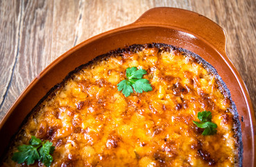 Stewed and baked white beans with spices in a vintage clay bowl on wooden table