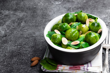 Cooked brussels sprouts with spinach and almonds on gray table