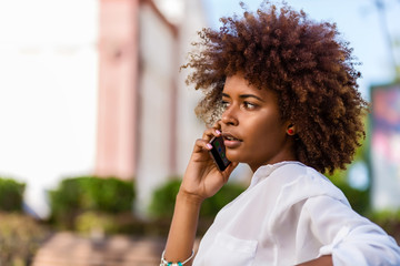 Outdoor portrait of a Young black African American young woman speaking on mobile phone