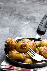 Baked baby potatoes with spices in a frying pan on gray stone table