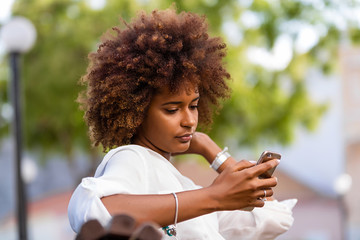 Outdoor portrait of a Young black African American young woman texting  on mobile phone