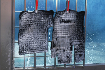 Rubber car mats are washed with soap suds. Cleaning with soap suds at self-service car wash. Soapy water runs down.