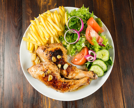 Zancas de pollo asado con patatas fritas y ensalada