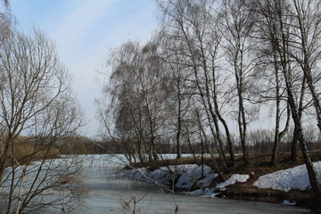 spring landscape with a river covered with ice and trees