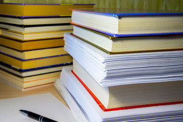 A stack of books and papers on the desktop, symbolizing learning, laws and regulations, a huge amount of information