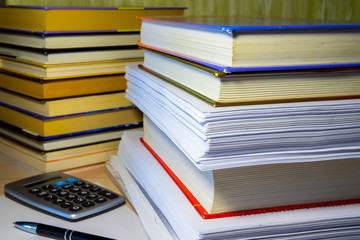 A stack of books and papers on the desktop, symbolizing learning, laws and regulations, a huge amount of information