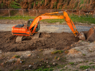 Old digger working on a construction site. Perimeter surrounded by metal fence.