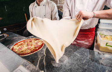 Preparation of a pizza dough, a dough in flight. - obrazy, fototapety, plakaty