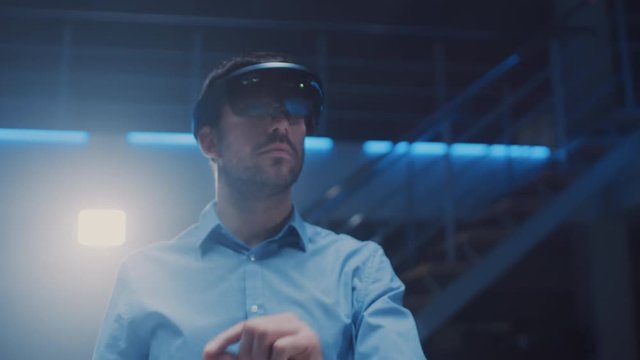 In 3D Content Creating Laboratory Engineer Wearing Professional Virtual Reality Headset Works and Gestures in Augmented Reality. Stylish Low Angle Arc Portrait Shot 