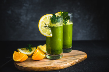 Fresh green juice made from parsley, oranges and lemons. Green smoothie with parsley on black...