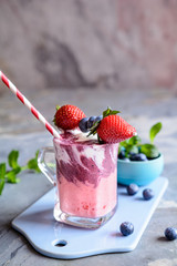 Strawberry and blueberry smoothie with yogurt, decorated with fruit skewer