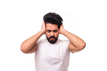 Fototapeta premium Closeup portrait young, angry, unhappy, stressed arab man covering his ears, looking up, to say, stop making loud noise it's giving headache, isolated white background. 