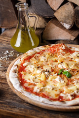 Pizza with chicken and pineapple on the background of firewood