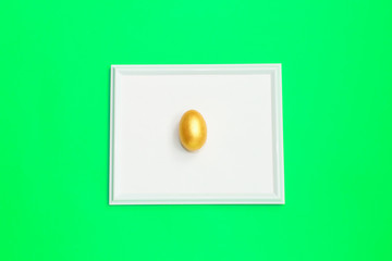 Frame with gold speckled easter egg with copy space for text on green background. Minimal Happy Easter concept. flatlay.