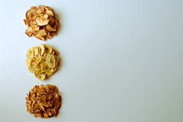 Healty organic chips on white background. Dehydrated banana, apple and coconut chips, top view.