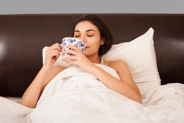 beautiful woman drinking coffee at bedroom in bed
