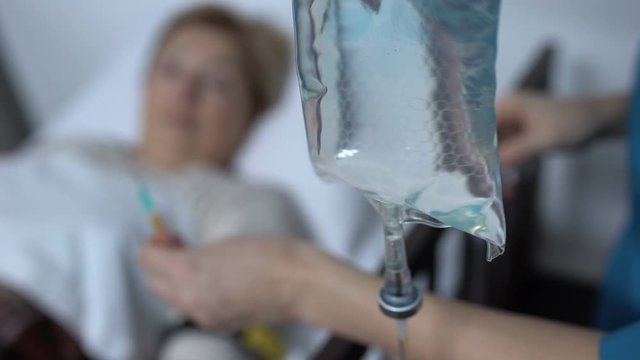 Dropper against ill patient lying in resuscitation ward, doctor making injection