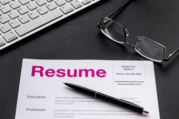 Review resumes of applicants set with keyboard and glasses black work desk background