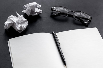 work desk of writer with notebook, glasses, pen on black background mock up