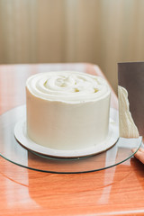 The confectioner levels the cream on the cake. The cook creates a cake, collects it and covers it with cream and then levels it with a spatula and a scraper.