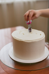 The confectioner levels the cream on the cake. The cook creates a cake, collects it and covers it with cream and then levels it with a spatula and a scraper.