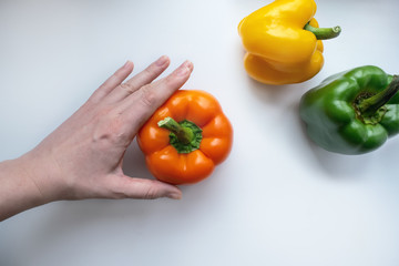 Hand holds orange bell pepper