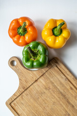 Different color peppers on wooden kitchen board