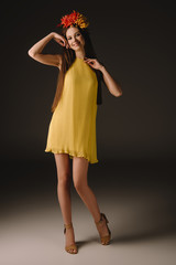 beautiful and brunette woman in elegant dress and wreath smiling and looking at camera