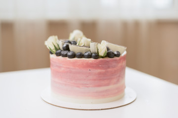 Beautiful pink cake with roses, cookies and blueberries.