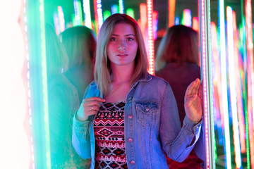 sweet caucasian girl walks in a mirror maze with colorful diodes and enjoys an unusual attraction...