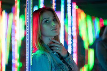 sweet caucasian girl walks in a mirror maze with colorful diodes and enjoys an unusual attraction...