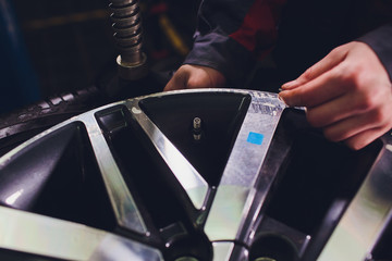 repairman balances the wheel and installs the tubeless tire of the car on the balancer in the...
