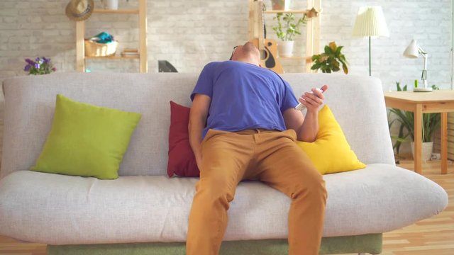 Unhealthy man feeling discomfort hemorrhoid pain sitting on the couch