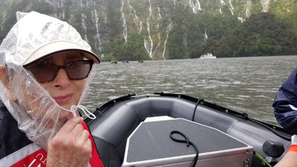 Woman in rubber boat in Milford Sound when it is raining and cold