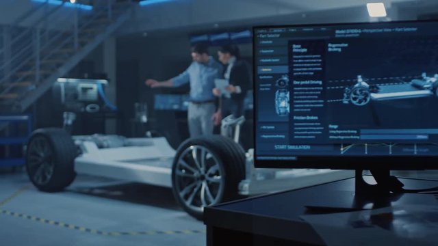 Auto Industry Design Facility Screens Show 3D Cad Software: Male Chief Engineer Shows Car Prototype to Female Inventor. Electric Vehicle Platform Chassis Concept Has Wheels, Engine and Battery