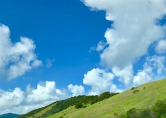 Fototapeta na wymiar Green California hills with blue sky and white clouds