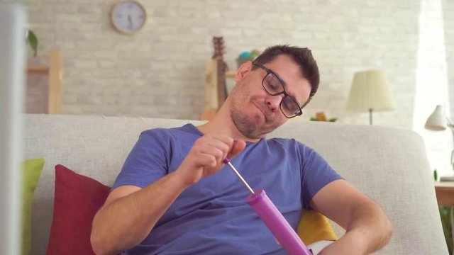 Man shakes a soccer ball with a pump sitting on the couch