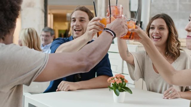 Four people or two couples happy toasting with cocktail at aperitif in city cafe.Medium portrait shot Friends italian trip in Umbria.4k slow motion