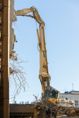 Obraz premium Closeup of destruction of building with hydraulic excavator/cutter crane. Reinforced concrete structures demolition