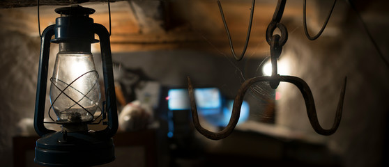 A close up of an old lamp in a basement. old rusty hooks for hanging meat- Halloween concept. - Image