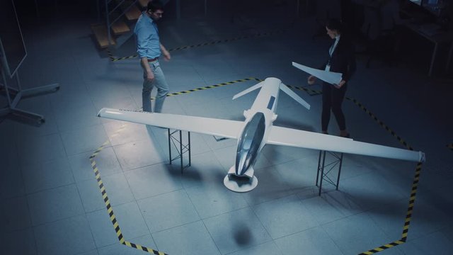 Meeting of Aerospace Engineers Work On Unmanned Aerial Vehicle / Drone Prototype. Aviation Experts have Discussion. Industrial Facility with Aircraft Capable of GPS Surveillance and Military Missions