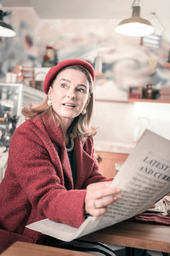 Kind blonde female holding newspaper in both hands