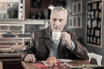 Delighted gray-haired man enjoying aroma coffee