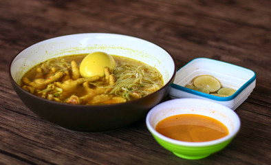 Soto ceker or chicken feet soup, chili sauce and lime on wood background. 